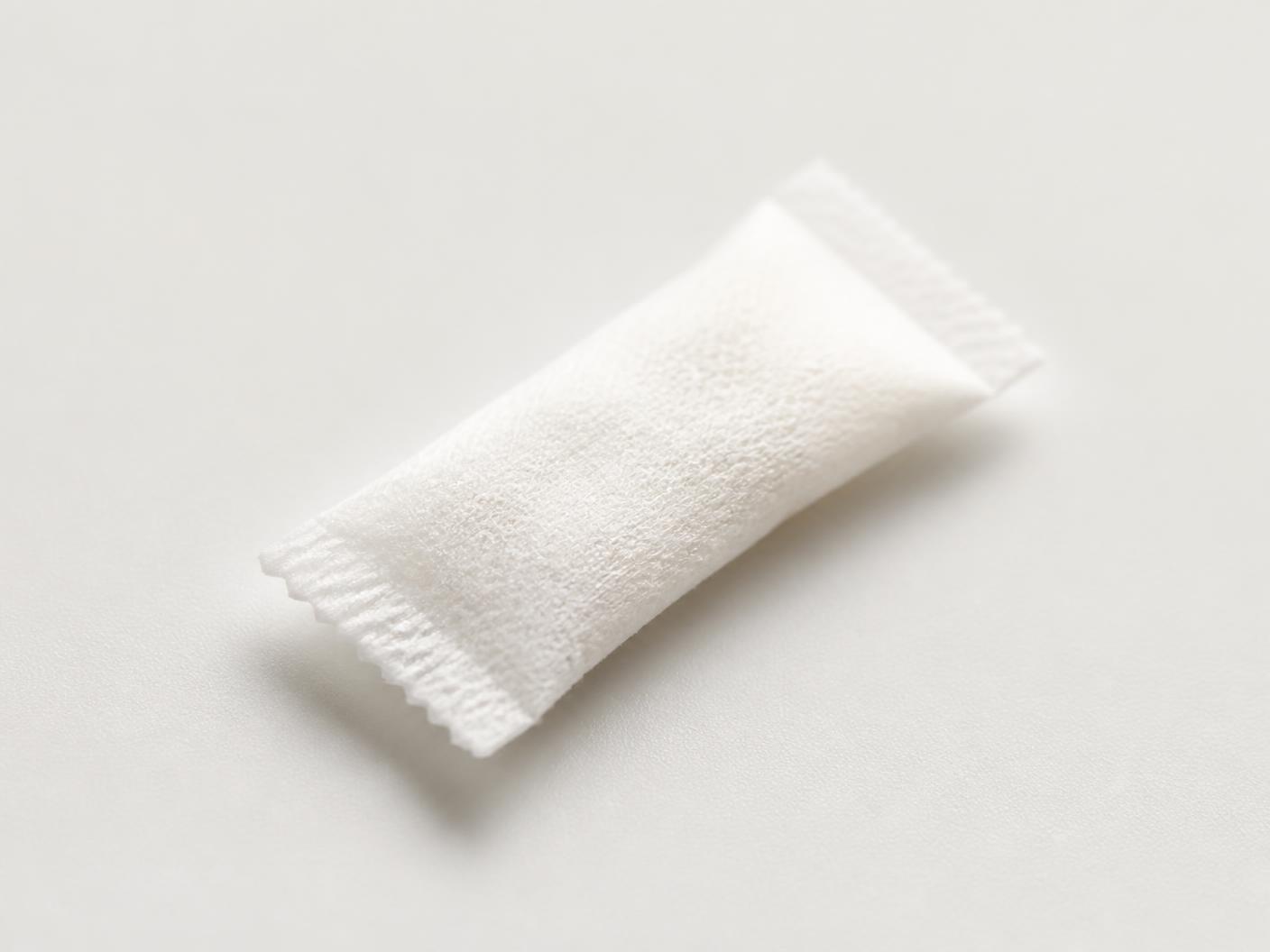 A single slim white KNA oral pouch on a pale surface